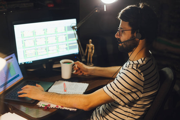 adult bearded man working sitting at home desk at computer, working online - Foto, Imagen