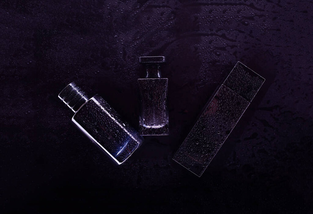 Three perfumes on a dark background - Foto, imagen