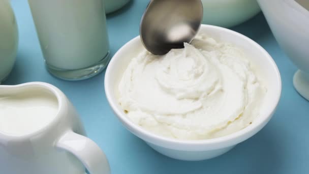 Χτυπημένη κρέμα γάλακτος με κουτάλι σε μπλε φόντο, κορυφαία προβολή - Πλάνα, βίντεο