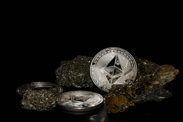 três moedas de éter de prata de moeda etérea e minerais com ferro sobre fundo preto - Foto, Imagem