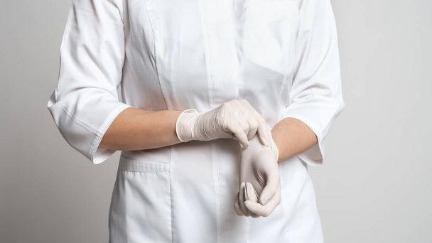 Обрезанный вид врача, надевающего белые латексные перчатки для защитного вируса. Защищайся. Медицина и здравоохранение - Фото, изображение