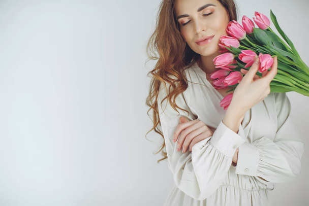 Piękna kobieta z tulipanami. Wiosenny bukiet w rękach młodej i szczęśliwej dziewczyny. - Zdjęcie, obraz
