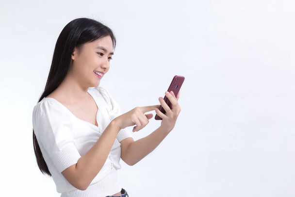 Portrait of beautiful asian girl Use the mobile phone happily on a white background - Photo, image