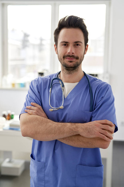 Porträt eines jungen lächelnden Arztes in der Arztpraxis                                - Foto, Bild