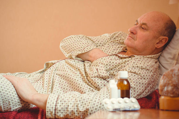 Preoccupato senior sdraiato a letto a casa. maturo uomo sdraiato a letto indossare in pigiama, sensazione di dolore, malato. - Foto, immagini