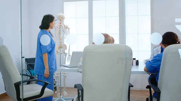 Medical nurse pointing on cervical spine of human skeleton - Photo, Image