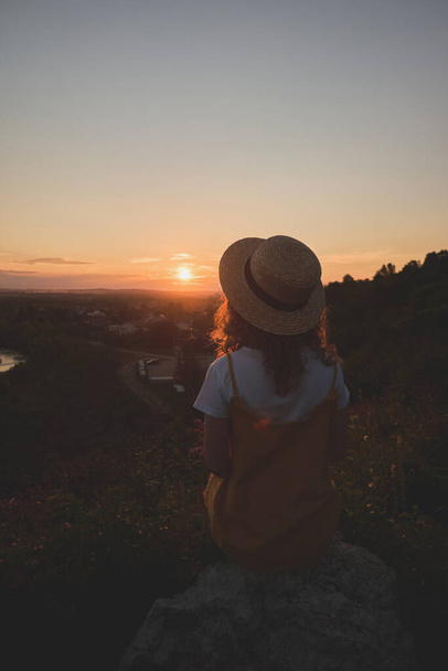 chica en un sombrero de paja sobre un fondo de puesta de sol - Foto, imagen