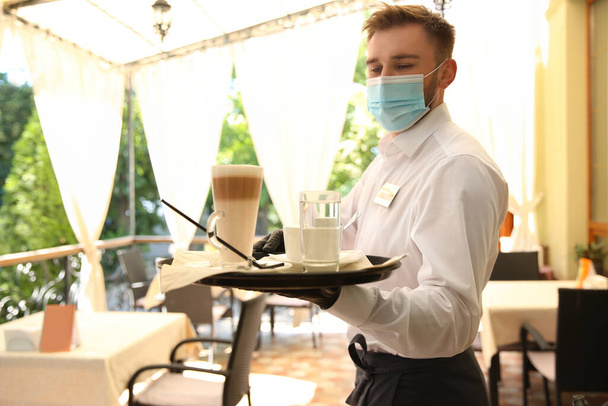 Waiter serving beverages in restaurant. Catering during coronavirus quarantine - Photo, image