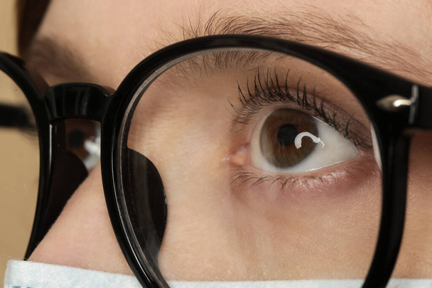 Imagen de primer plano de la mujer con gafas para los ojos y máscara médica desechable. Medida de protección durante la pandemia del coronavirus.  - Foto, imagen