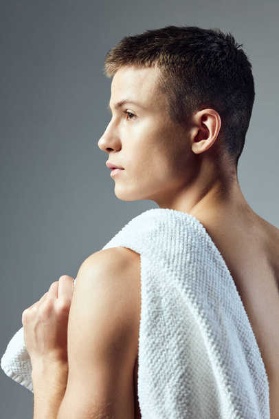 Όμορφος άντρας με πετσέτα στην πλάτη του σε γκρι φόντο πίσω όψη - Φωτογραφία, εικόνα