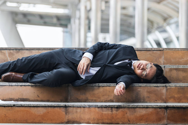 Втомлений молодий бізнесмен азіатського походження лежав на сходах і страждав від важкої депресії. Безробіття і концепція звільнення. - Фото, зображення