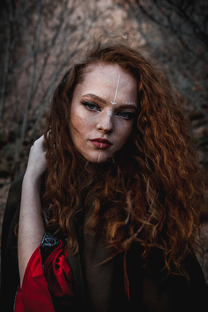 秋の森の中の歴史的なケルトの衣装を着た赤い髪の女性 - 写真・画像