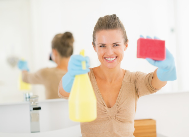 Housewife showing spray bottle and sponge - Valokuva, kuva