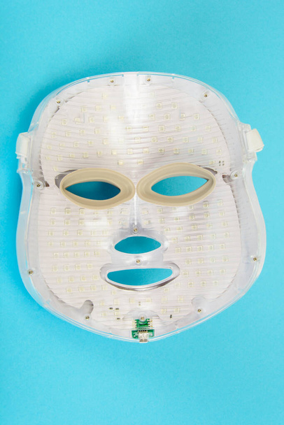 LED gezichtsmasker. Een apparaat voor het verlichten en verjongen van de huid. Collageentherapie. Foto van de studio - Foto, afbeelding