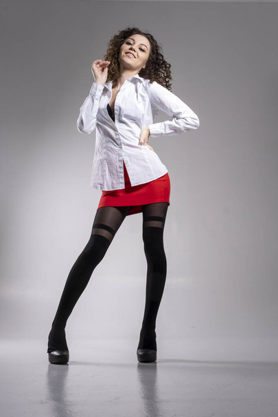 Girl in pantyhose, red skirt and white shirt. Studio portrait. - Photo, Image
