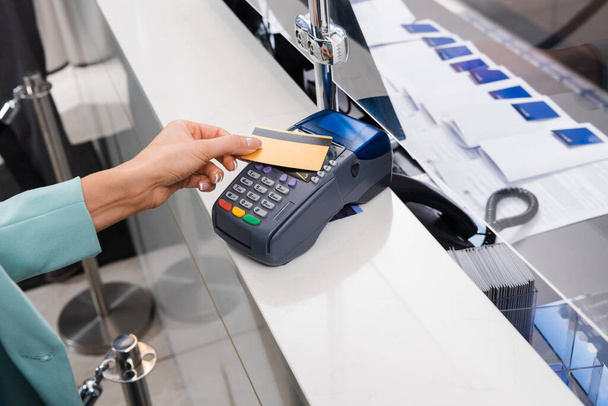 Oříznutý pohled na ženu platící kreditní kartou a platebním terminálem v hotelu  - Fotografie, Obrázek