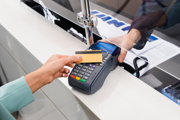 Cropped view of receptionist holding payment terminal near woman with credit card in hotel  - Foto, Bild