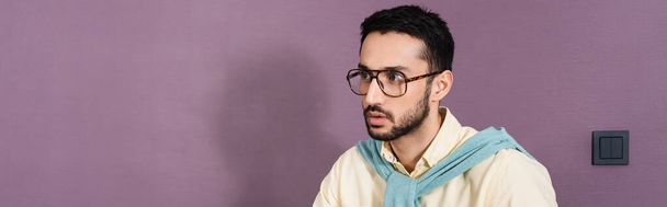 Muslim man in eyeglasses looking away in hotel room, banner  - 写真・画像