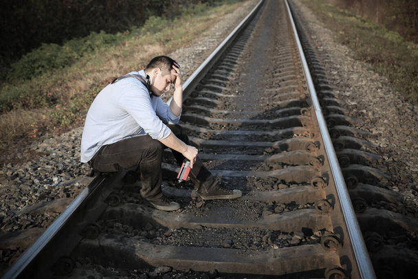 Alkoholos férfi a vasúti síneken a szabadban. Depressziós betegség. Gazdasági válság, szegénység, munkanélküliség. A karantén alatt izolált koronavírus következményei. Reménytelenség. - Fotó, kép