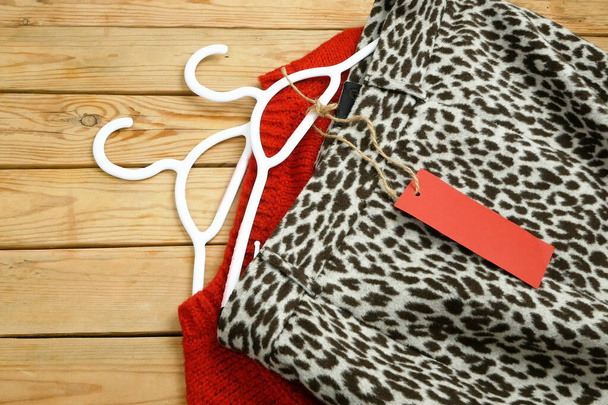suéteres y falda en perchas sobre fondo de madera con etiqueta de precio rojo, concepto de ventas de invierno - Foto, imagen