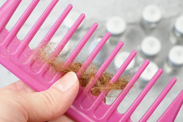 hair loss problem. Bottles with medicine, hairbrush and hair bun. alternative treatments medication bottles and comb on gray background, closeup - Photo, Image