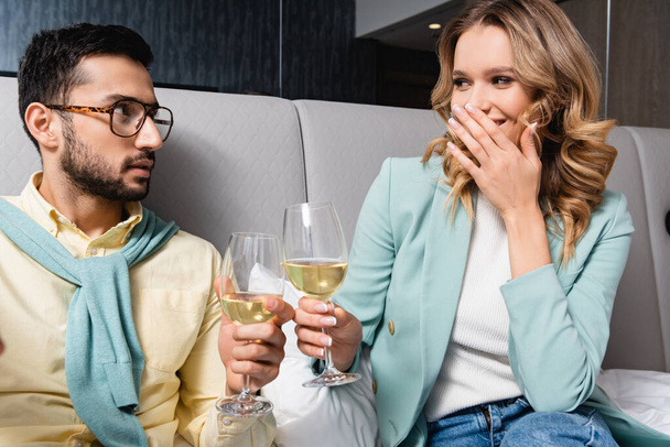 Femme joyeuse toasting vin avec petit ami musulman à l'hôtel  - Photo, image