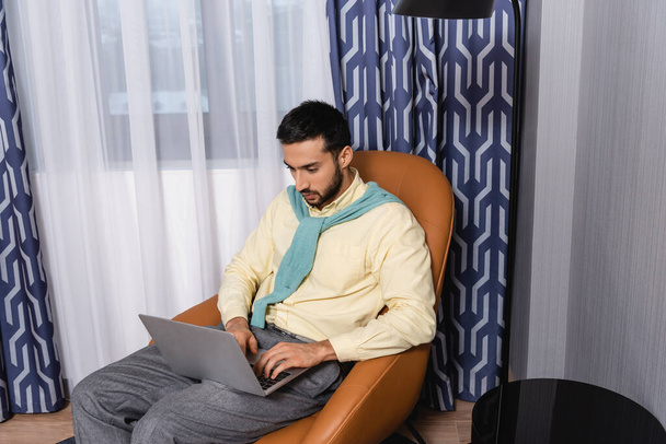 Joven musulmán freelancer utilizando el ordenador portátil en la habitación de hotel  - Foto, Imagen