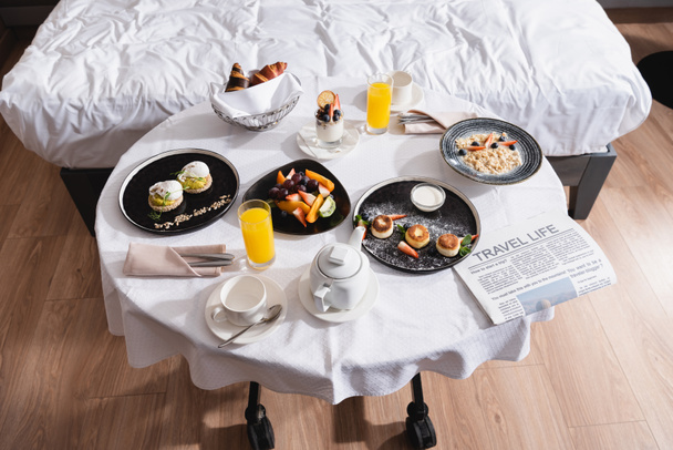 High angle view of tasty breakfast and newspaper on table in hotel  - Photo, Image