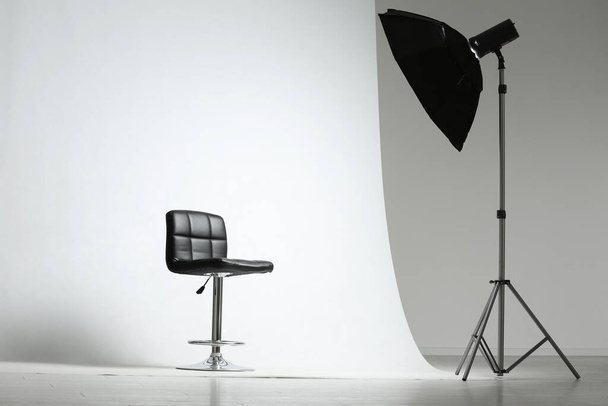 Modern chair and professional lighting equipment in photo studio - Fotó, kép