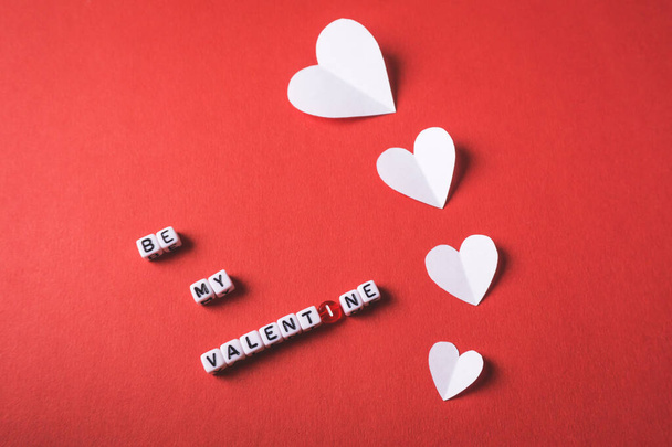 Sei mein Valentinstag-Text mit quadratischen Perlen Buchstaben mit weißen Papierherzen auf rotem Hintergrund - Foto, Bild
