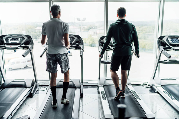 Two men on a treadmill in a modern gym, in front of them are large panoramic windows. - Foto, Imagem