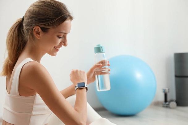 Young woman wearing smart watch during training indoors, space for text - Foto, Bild