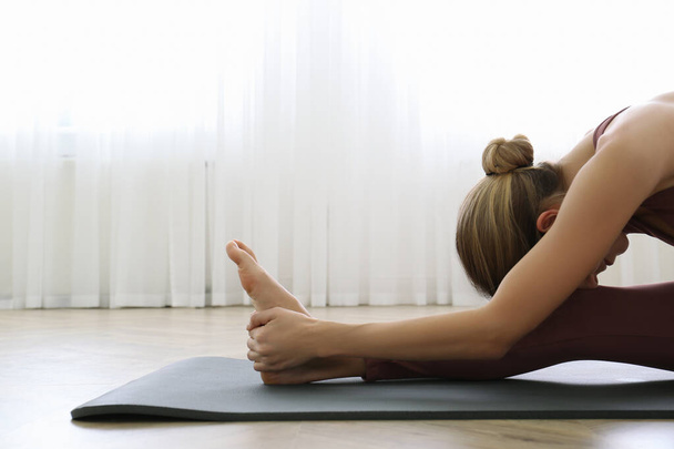 Young woman practicing head to knee asana in yoga studio. Janu Sirsasana pose - Fotoğraf, Görsel