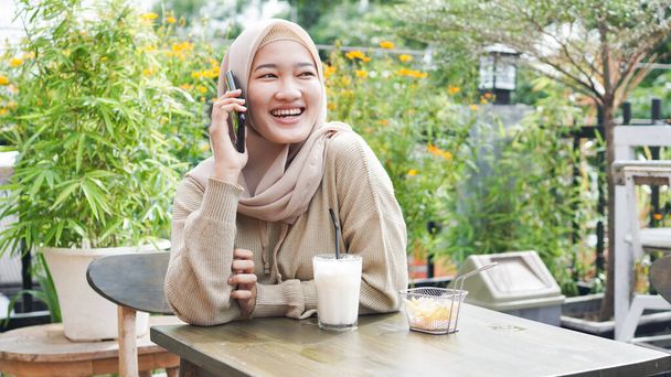 glücklich Asia Hijab Frau mit Smartphone und Anruf, sitzt im Café - Foto, Bild
