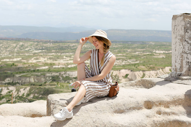 Girl sitting on rock, beautiful landscape in background, Cappadocia. - Photo, Image
