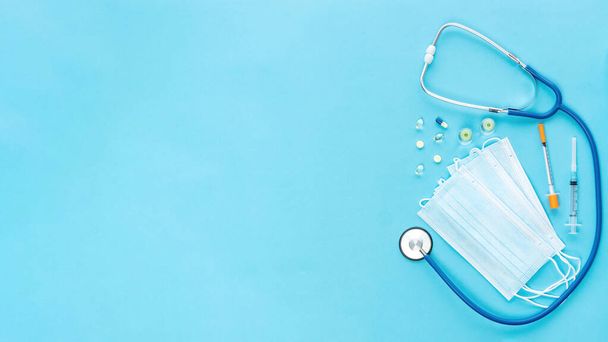 Stethoscope, syringes, vaccine, masks and pills for advertising banner of medical services for COVID-19 vaccination, health and life insurance. Medical banner with blue background and copy space. - Photo, Image