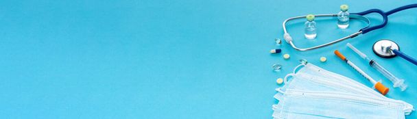 Медицинская посуда и инструменты на синем фоне с копировальным пространством для длинного баннера или заголовка. КОВИД-19 вакцинация для рекламного баннера медицинских услуг, поликлиники, страхования жизни и здоровья - Фото, изображение