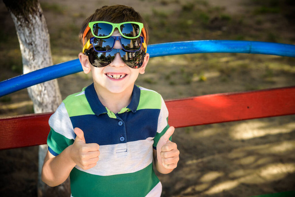 Retrato de uma criança menino alegre em vários óculos de sol ao ar livre. Beleza, moda casual verão. Óptica para crianças. Protecção solar. - Foto, Imagem