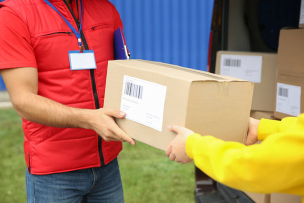 Courier giving package to customer outdoors, closeup - Photo, Image
