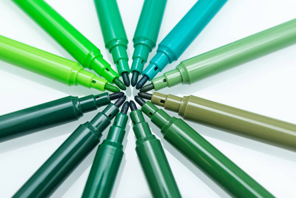 Close up of green colored felt-tip pens on isolated background. Selective focus. Different shades of green. Concept of taking care of ecology and environment - Photo, Image