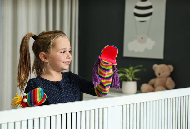 Cute little girl performing puppet show at home - Foto, imagen