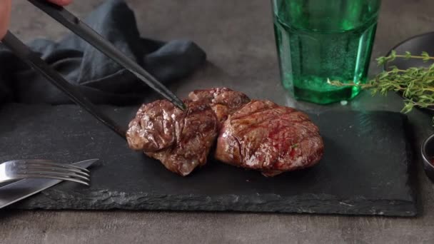 cuoco mette appena alla griglia bistecca di manzo caldo succosa su un piatto di pietra nera e decora con timo  - Filmati, video