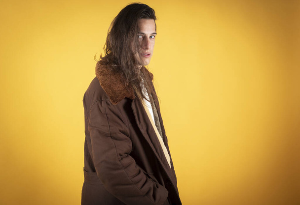 a man in a fur jacket, with long hair looking serious, orange background copy space - Photo, image