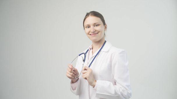 Portret atrakcyjnej młodej lekarki w białym płaszczu. - Zdjęcie, obraz