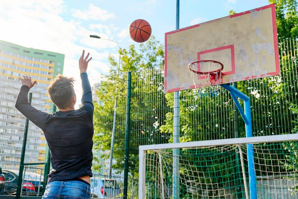 Teenage guy playing street basketball. Active lifestyle of teenagers - Photo, Image