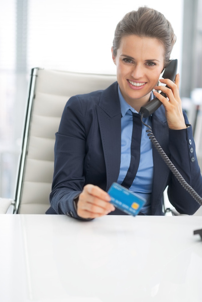 Business woman with credit card talking phone - 写真・画像
