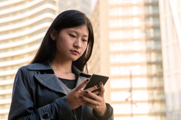 jovem mulher asiática elegante consultando seu telefone celular na cidade, tecnologia e conceito de estilo de vida urbano, espaço de cópia para texto - Foto, Imagem