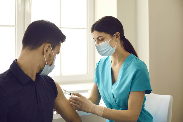Professional nurse or doctor injects a patient with a flu or coronavirus vaccine in a modern clinic. - Foto, imagen