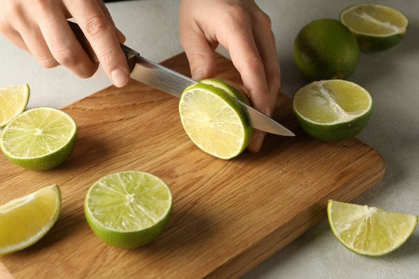 Woman cuts lime on cutting board, close up - Фото, зображення