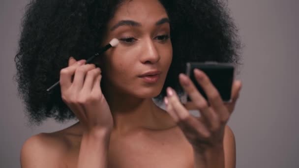 jeune femme afro-américaine appliquant surligneur isolé sur gris - Séquence, vidéo